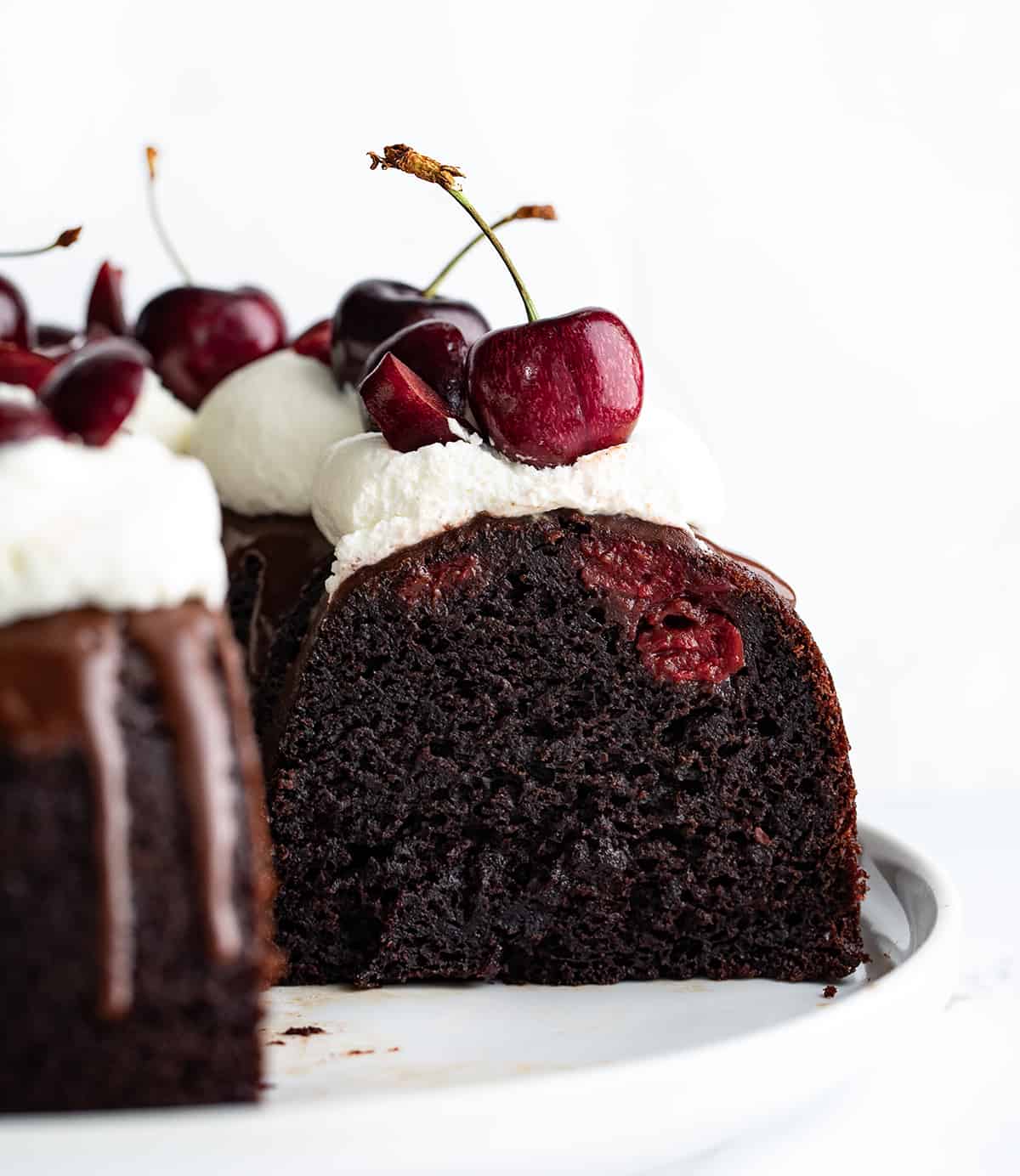 Black Forest Bundt Cake on a White Serving Platter with Pieces Removed Showing Inside Texture.