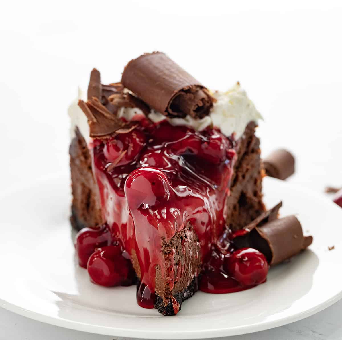 One Piece of Black Forest Cheesecake on a White Plate and Backlit.