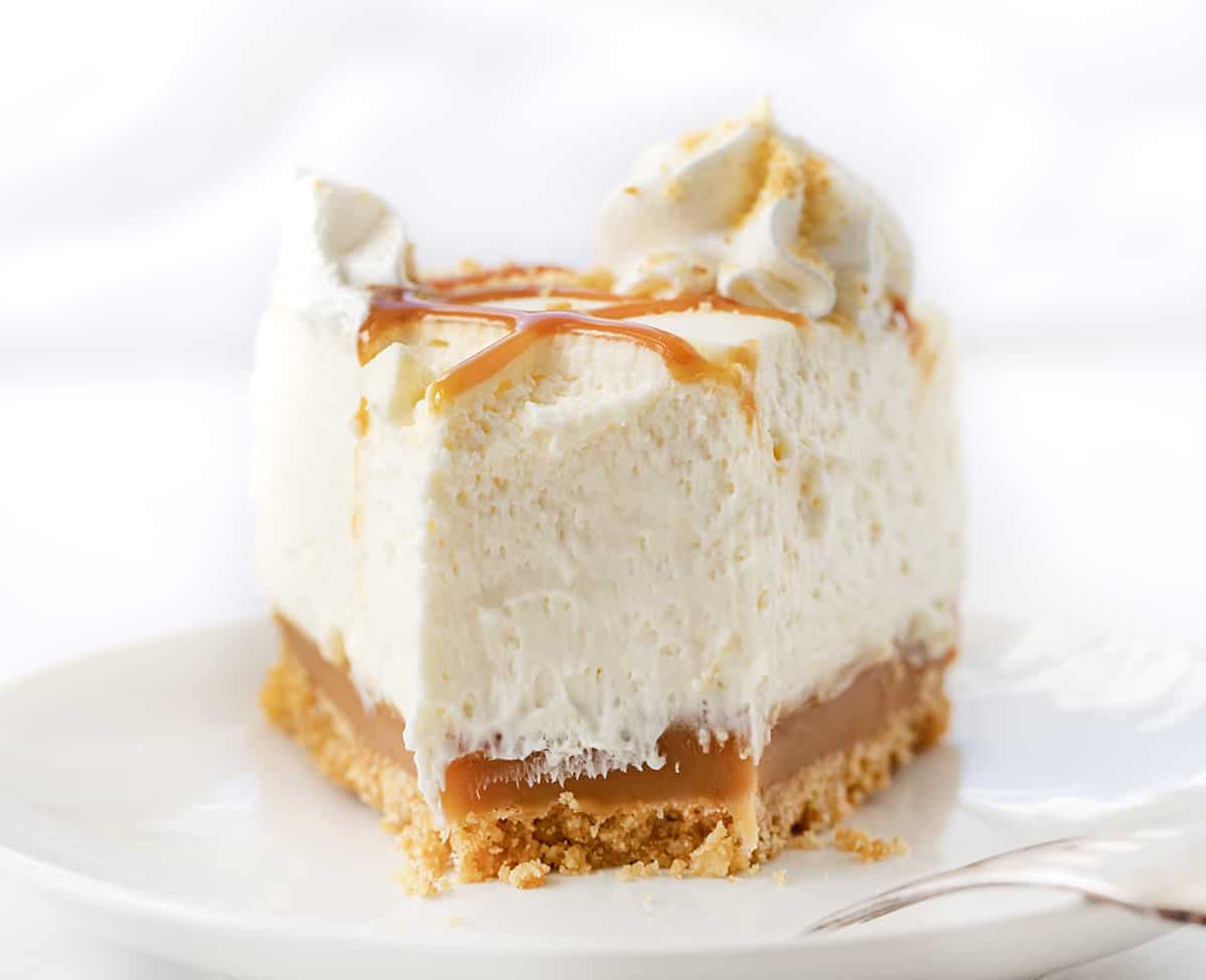 Piece of Caramel Cheesecake with Bite Removed on a White Plate.