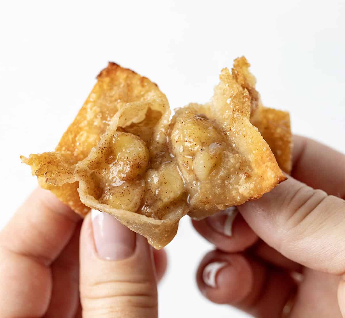 Hand opening a fried banana bite showing the inside texture.