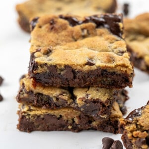 Stack of Hot Fudge Chocolate Chip Cookie Bars on a White Counter with Other Bars Around.
