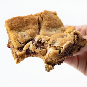 Hand Holding Peanut Butter Chocolate Chip Cookie Bar with a Bite Removed.