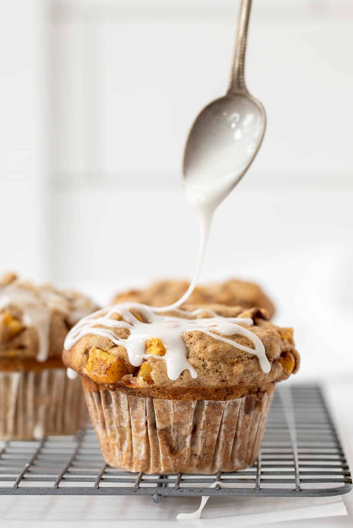 Drizzling Glaze over Peach Muffins on a Cooling Rack.