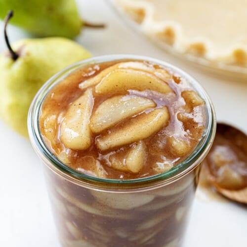 Jar of Pear Pie Filling on a Counter Next to Pie Crust and Pears.