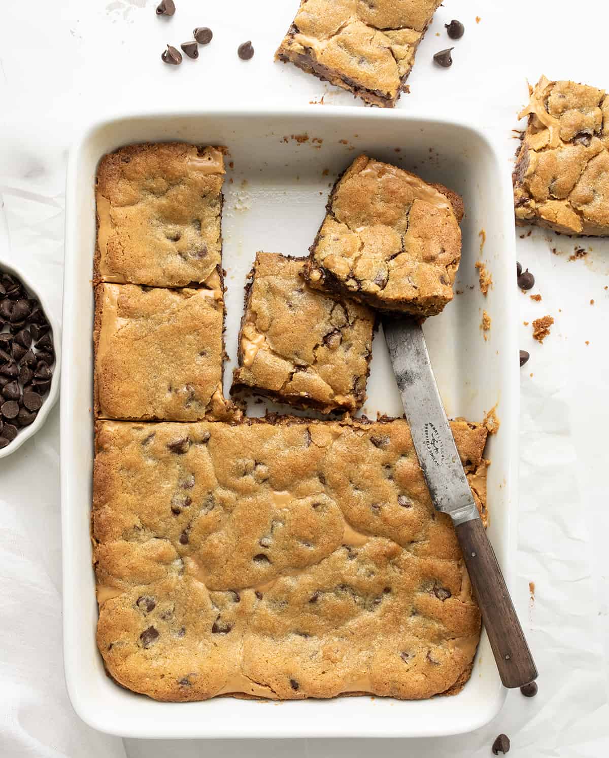 Peanut Butter Chocolate Chip Cookie Bars in a White Pan from Overhead with Some Bars Cut and Removed.