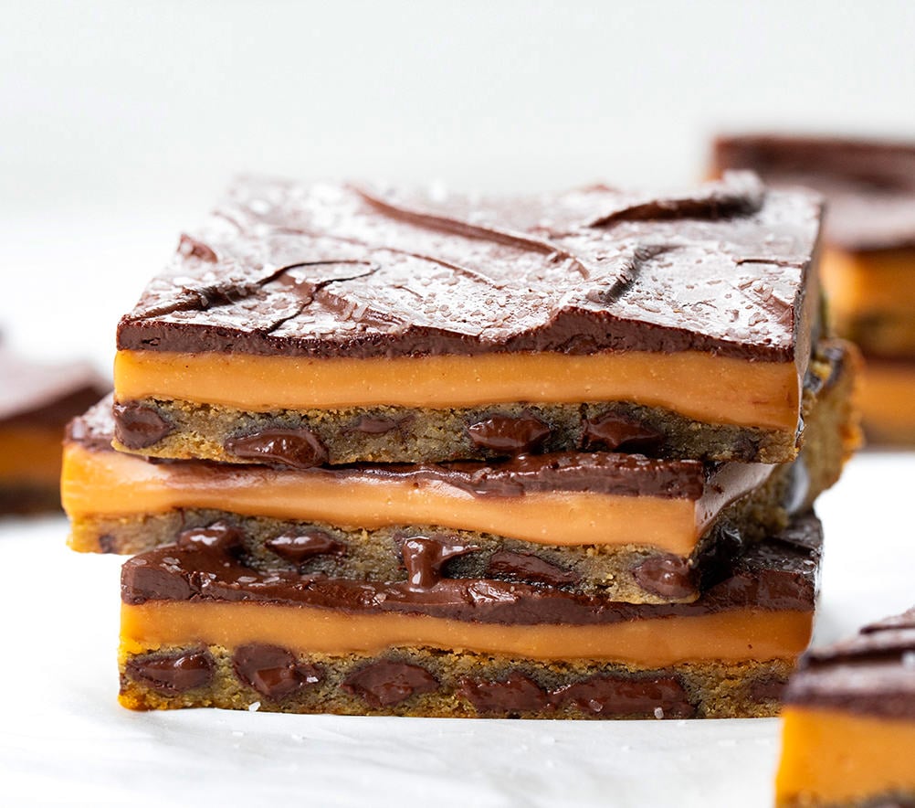 Stack of Salted Caramel Cookie Bars Showing Layers on a White Counter.