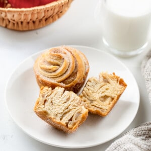 Apple Pie Cruffins on a white plate with one cut in half showing the apple pie filling inside.