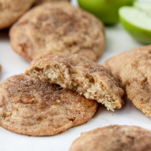 Apple Snickerdoodles on a White Counter with one cookie halved showing inside texture.