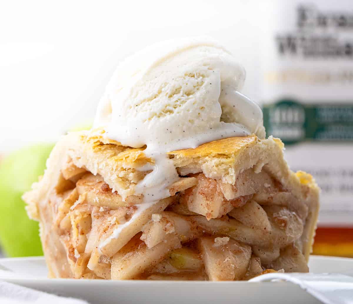 Piece of Bourbon Apple Pie on a Plate with a Bite Removed in Front of Bourbon Bottle.