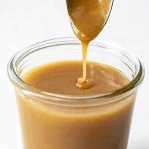 Spoon Drizzling Butterscotch Sauce into Glass Jar.