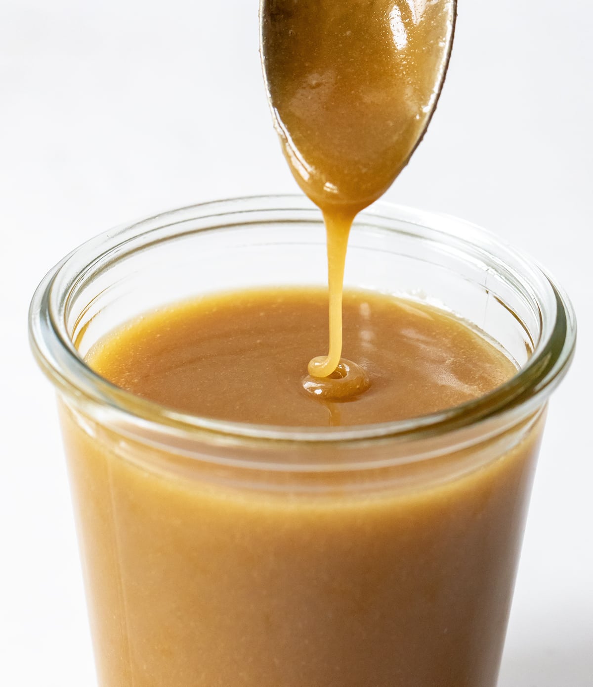 Spoon Drizzling Butterscotch Sauce into Glass Jar.