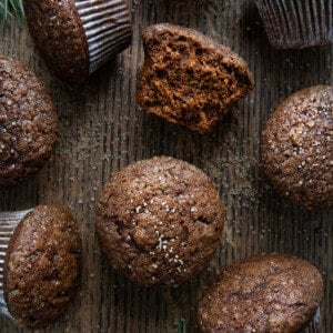Gingerbread Muffins on a Dark Table with Muffins scattered aaround and one halved showing inside texture.