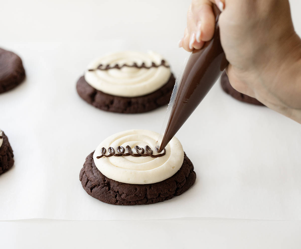 Piping Chocolate Swirl onto a Marshmallow Dream Cookies.