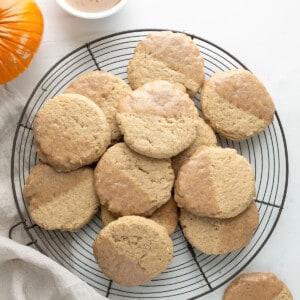 Tray of Pumpkin Spice Butter Cookies on a White Table with Towel and Glaze in a bowl from Overhead.