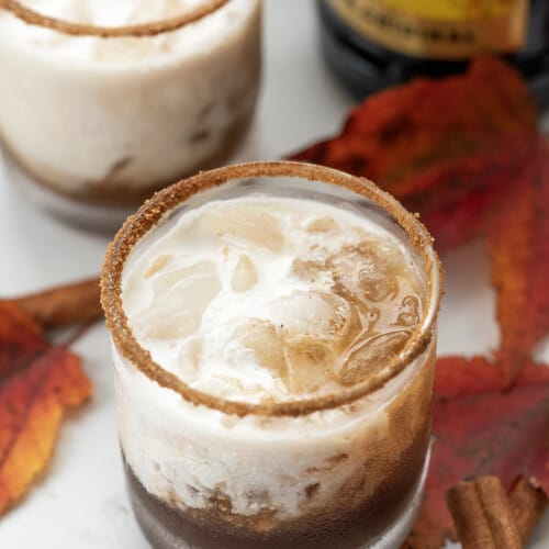 Glasses of Pumpkin Spice White Russian Cocktail with Leaves and a Kahlua Bottle.