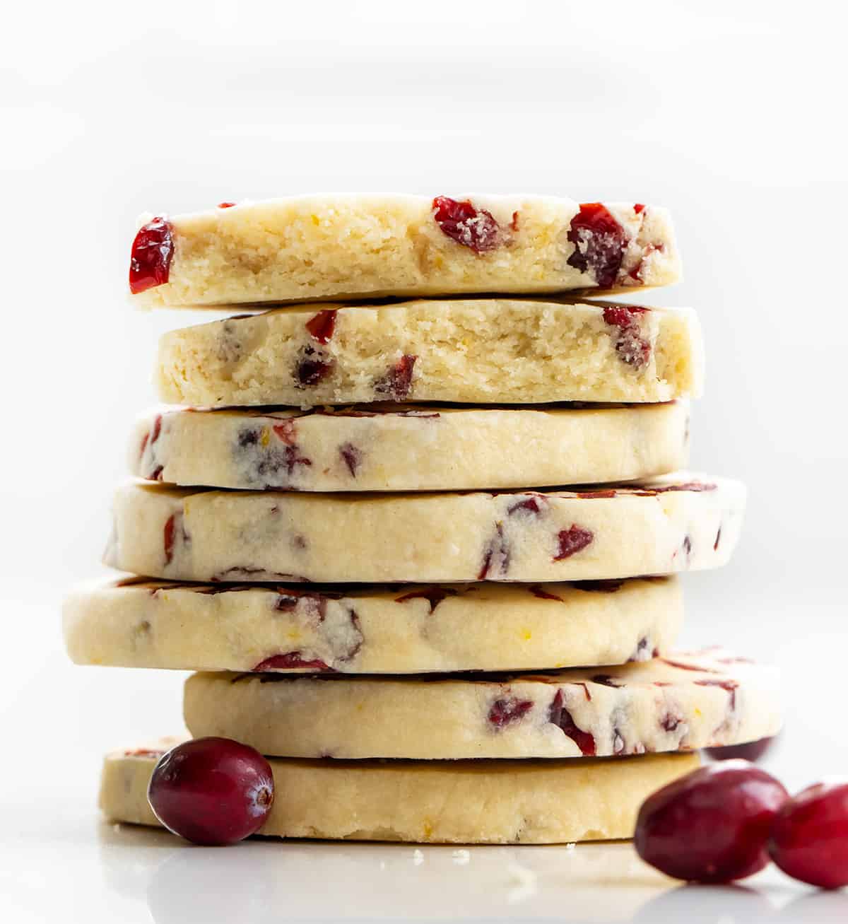 Stack of Cranberry Orange Shortbread Cookies with top cookie halved showing inside texture.