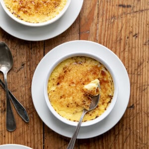 Spoon in a bowl of Créme Brûlée on a wooden table.