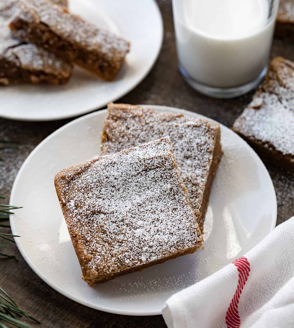 Plate of Gingerbread Brownies on a wooden table with milk.