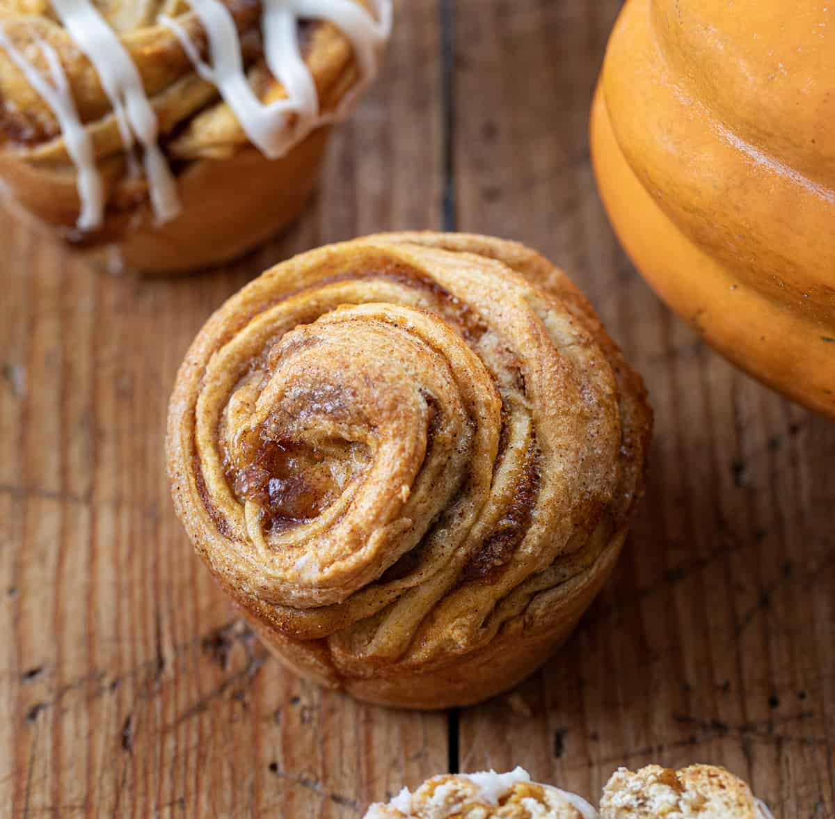 One Pumpkin Spice Cruffins on a Wooden Table near a pumpkin.