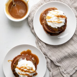 Two white plates with Sticky Toffee Pudding on them and more sauce.