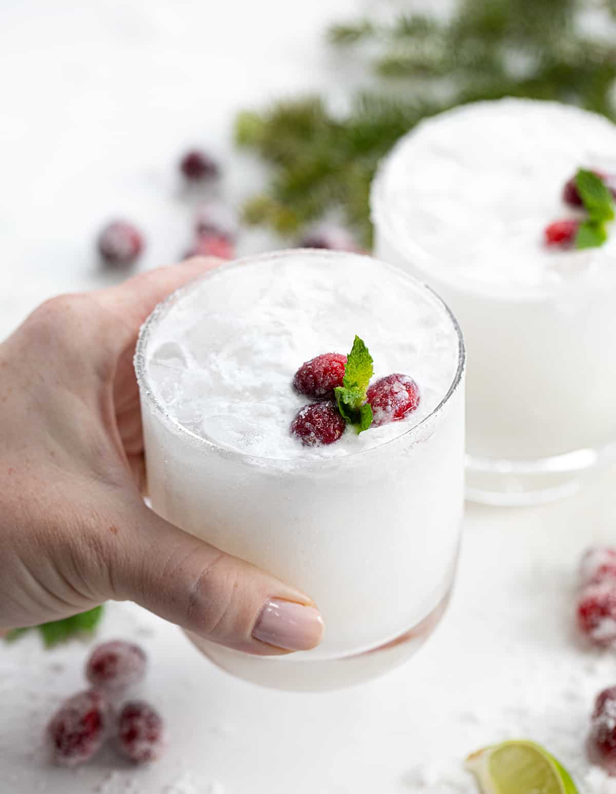 White Christmas Mojitos surrounded by sugared cranberries.