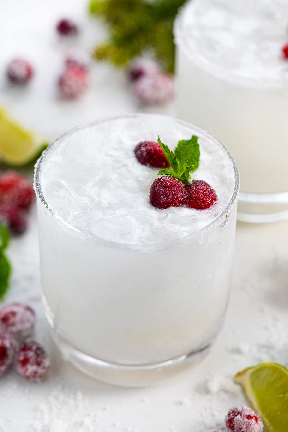 White Christmas Mojitos surrounded by sugared cranberries.