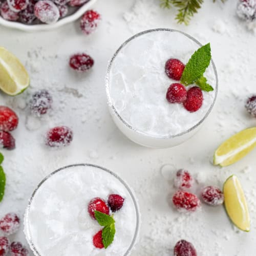 White Christmas Mojitos surrounded by sugared cranberries.