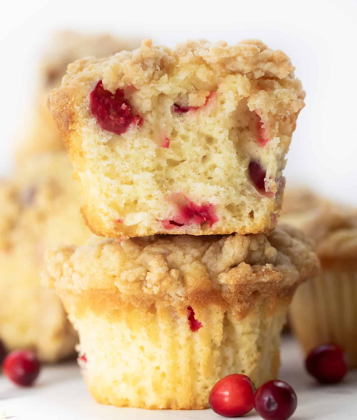 Cranberry Cream Cheese Muffins stacked with top muffin halved showing inside texture.