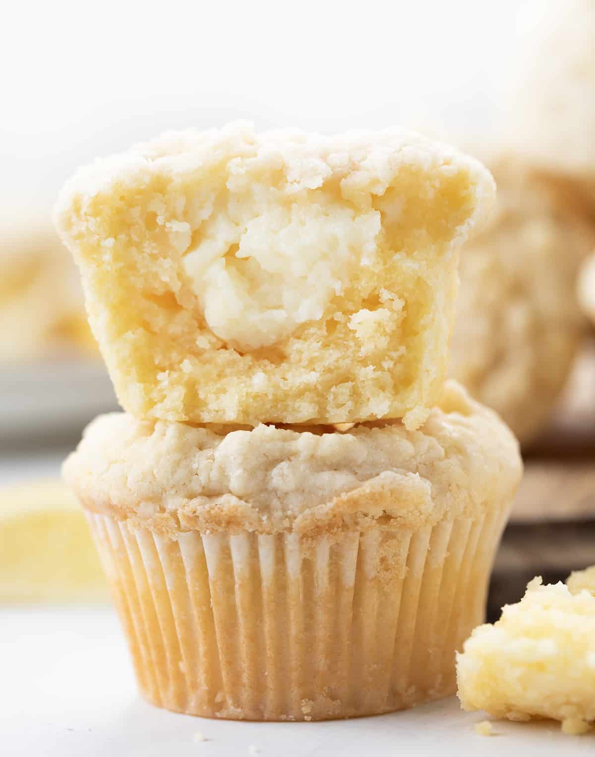 Two Lemon Cream Cheese Muffins with top muffin halved so you can see the inside texture and cream cheese.