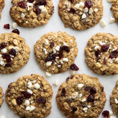 White Chocolate Cranberry Oatmeal Cookies on a white table spread out from overhead.