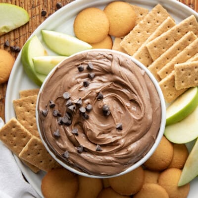 Bowl of Brownie Batter Dip on a platter with apples and cookies.
