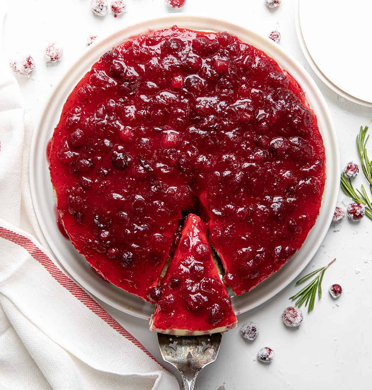 Removing one piece of Cranberry Cheesecake from serving plate from overhead.