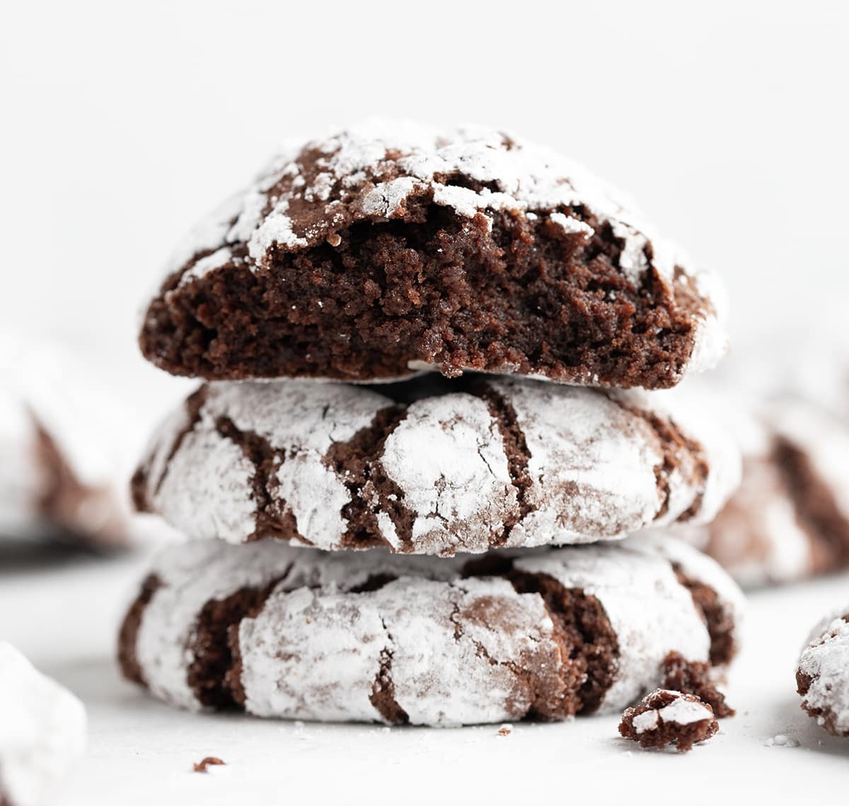 Stack of Chocolate Crinkle Cookies with top cookie halved showing inside texture.