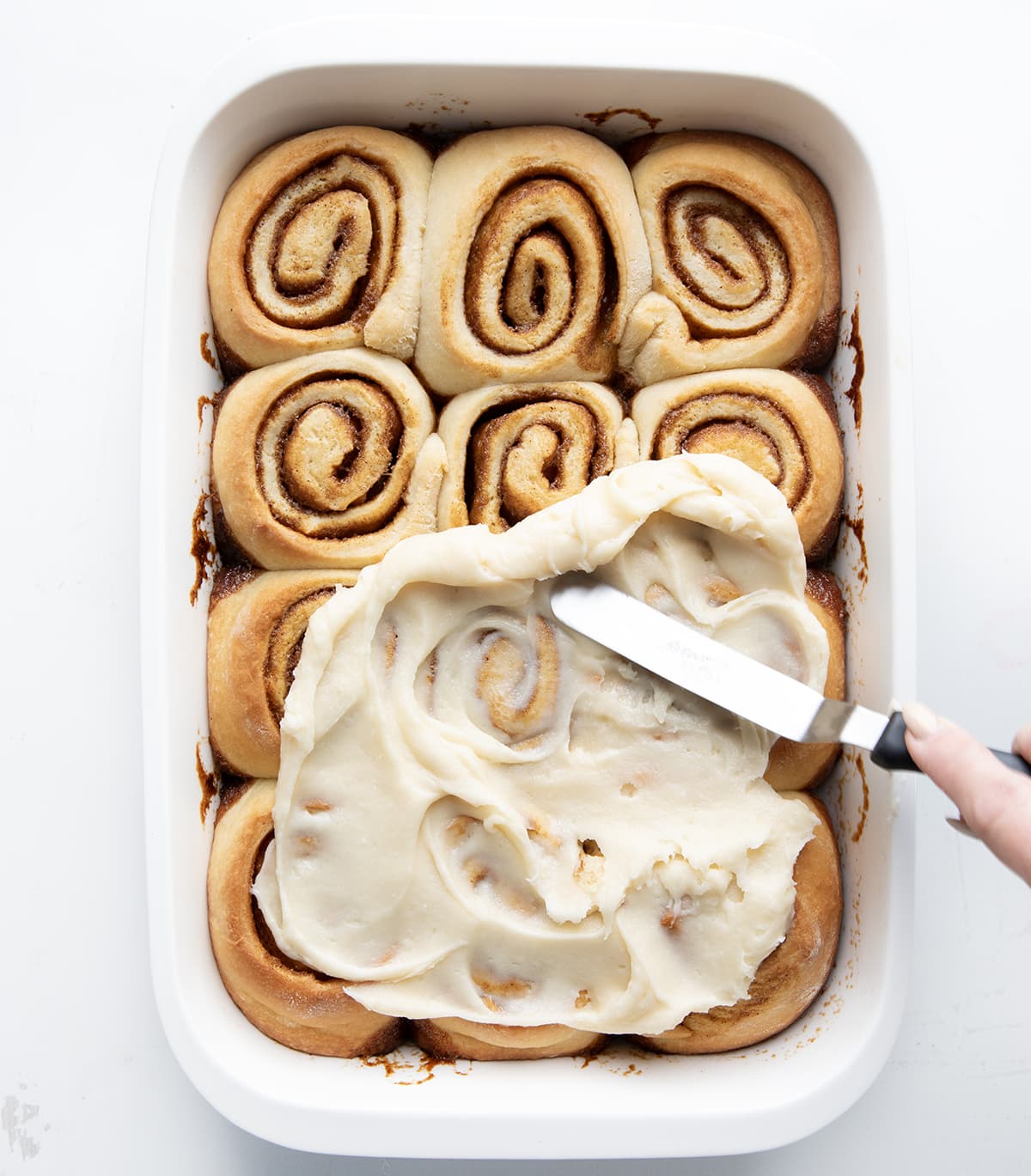 Spreading frosting over Gingerbread Cinnamon Rolls.