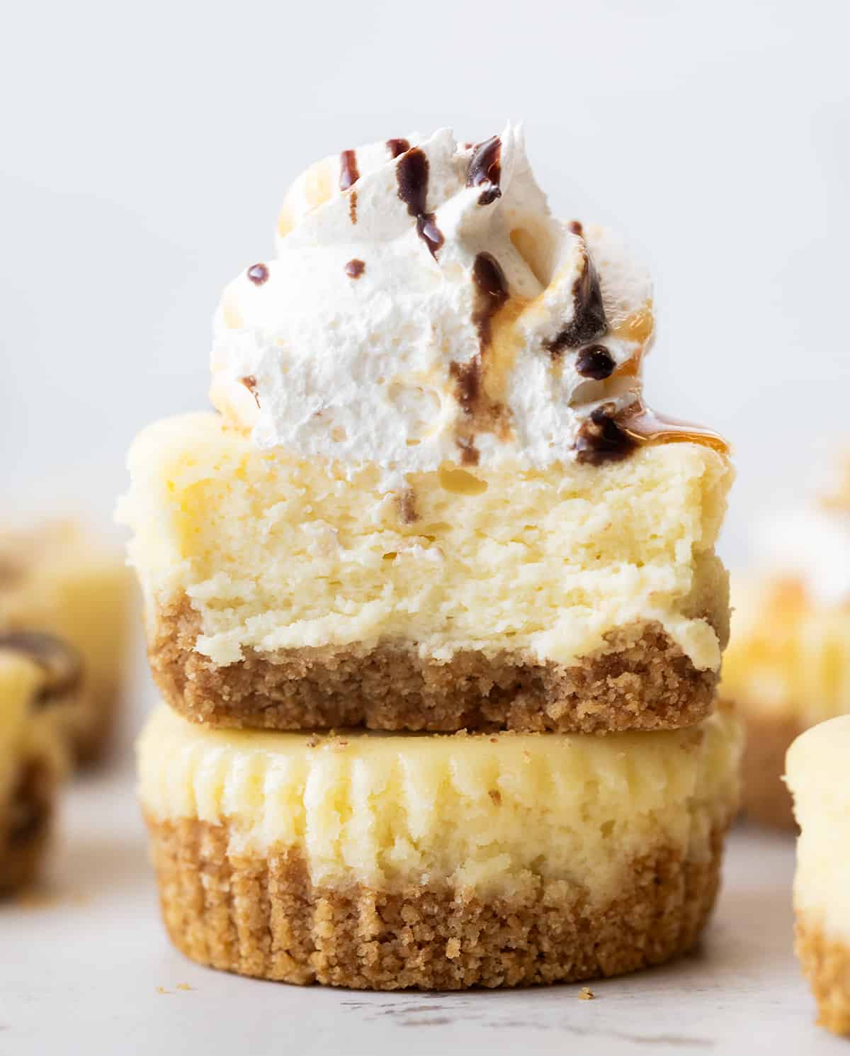 Mini Cheesecakes stacked with top cheesecake cut in half showing tender inside.