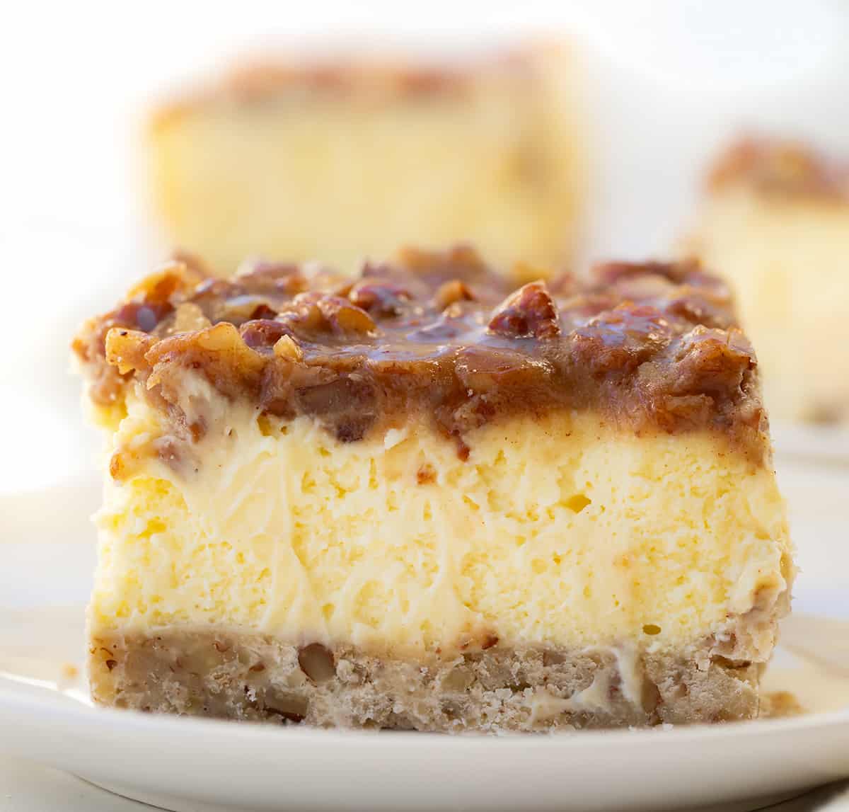 One Pecan Pie Cheesecake Bar on a white plate showing texture.
