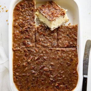 Pan of Pecan Pie Cheesecake Bars with some cut up and one sitting up slightly.