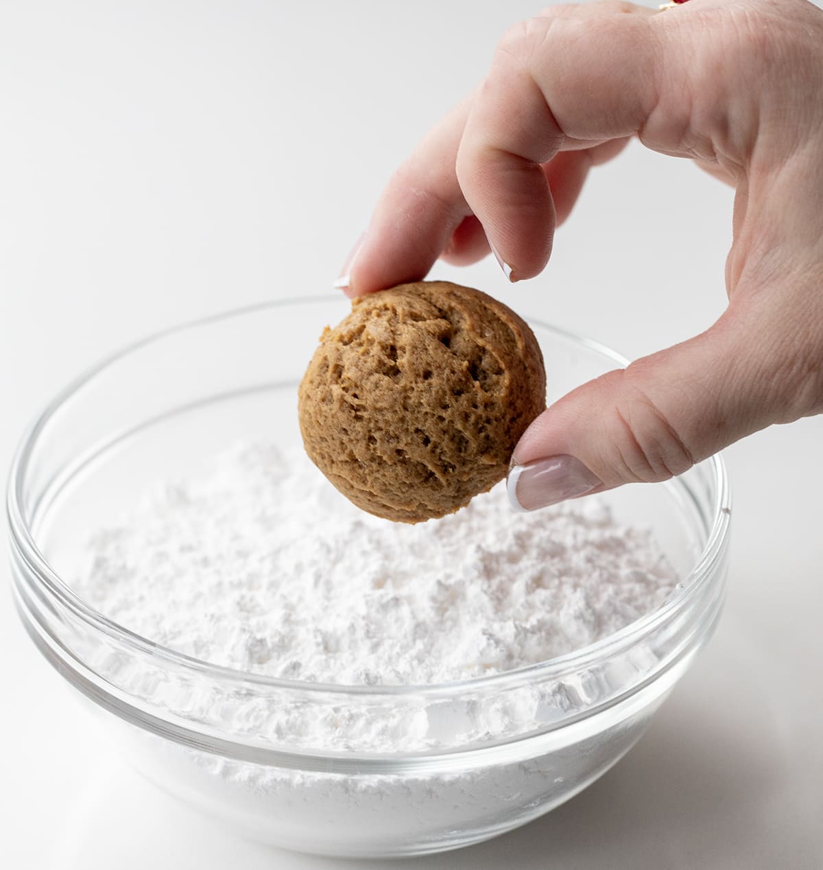 Dipping a Pfeffernüsse Cookie in confectioners sugar.