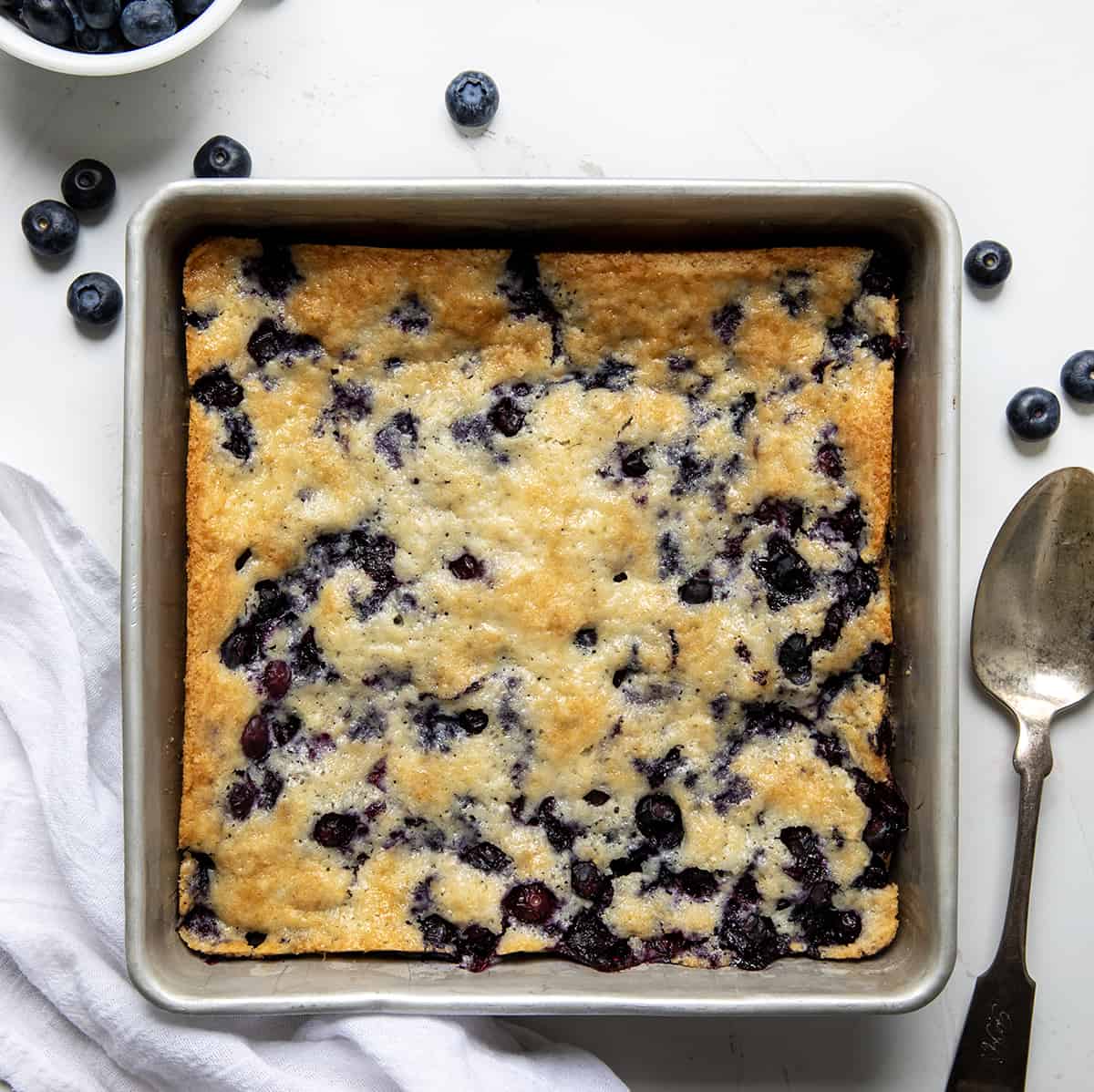 Pan of Bisquick™ Blueberry Cobbler on a white table from overhead.