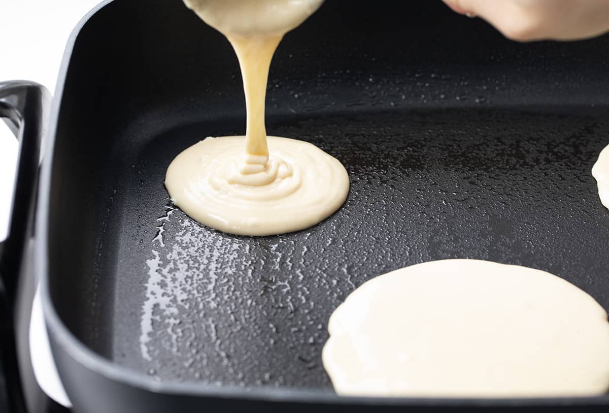 Pouring batter into a skillet to make Homemade Bisquick Pancakes.