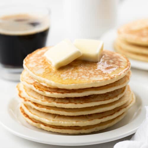 Stack of Homemade Bisquick Pancakes on a white plate on a white table.