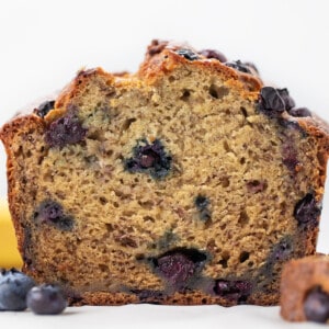 Loaf of Blueberry Banana Bread on a white counter cut in half showing inside.