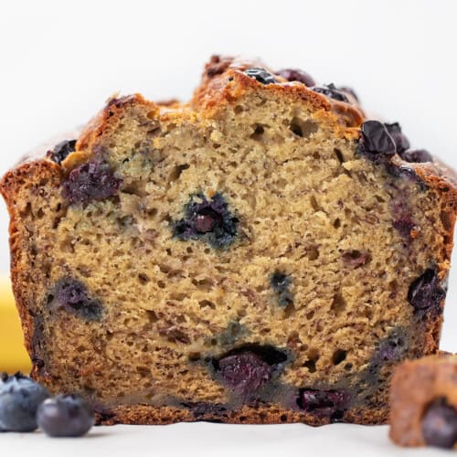 Loaf of Blueberry Banana Bread on a white counter cut in half showing inside.