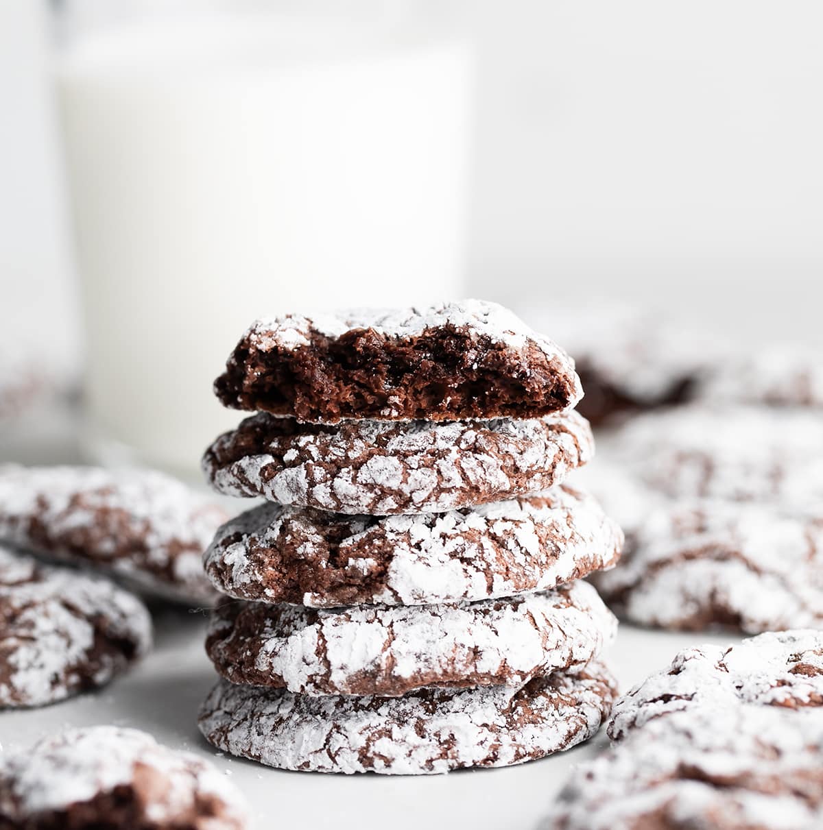 Stack of Cool Whip Cookies with top cookie halved showing inside and a glass of milk behind it.