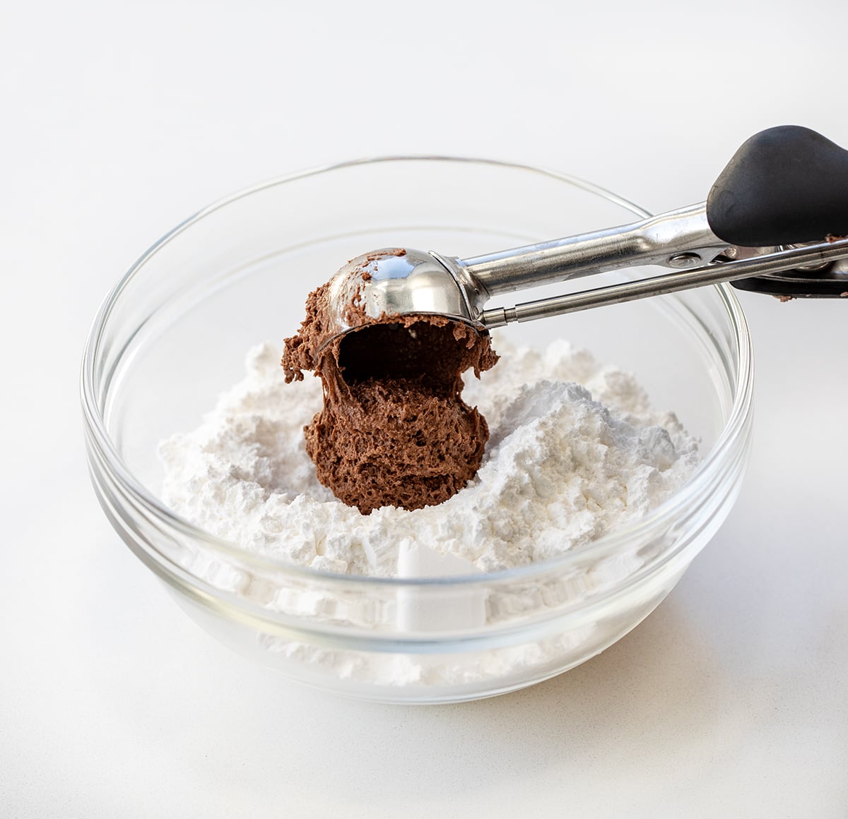 Adding scoop of Cool Whip Cookie dough to bowl of confectioners sugar .