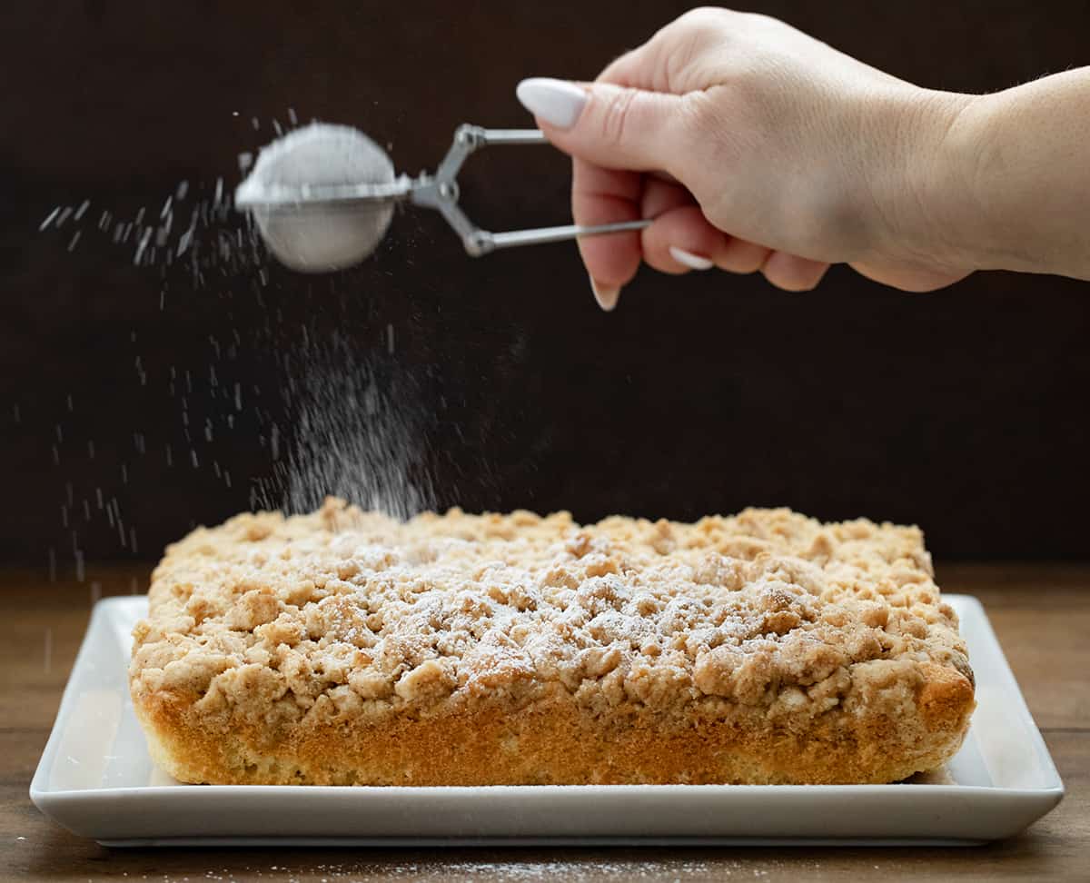 Dusting Crumb Cake with confectioners' sugar.