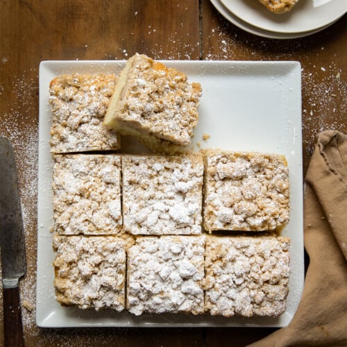 Plate with Crumb Cake on it cut into pieces with one piece on its side.