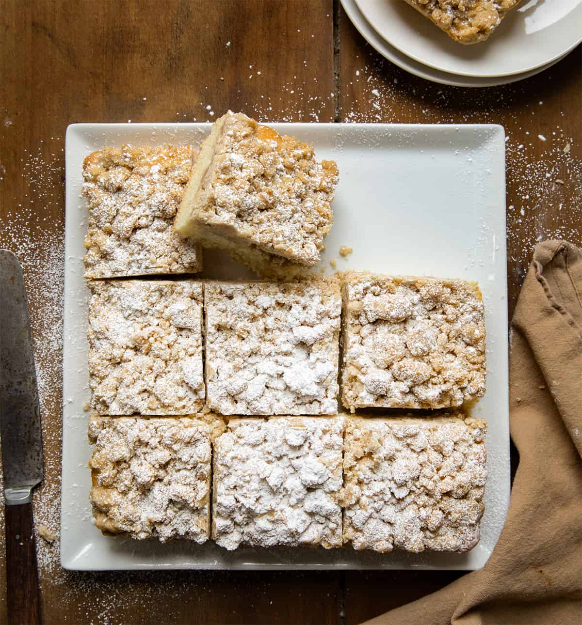 Plate with Crumb Cake on it cut into pieces with one piece on its side. 