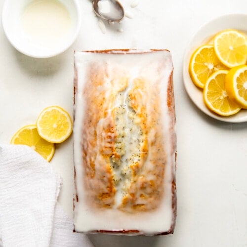 Loaf of Lemon Poppy Seed Bread on a white table covered in glaze from overhead.