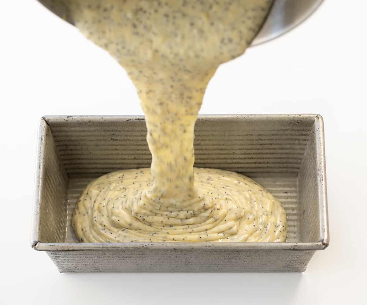 Pouring Lemon Poppy Seed batter into a pan.
